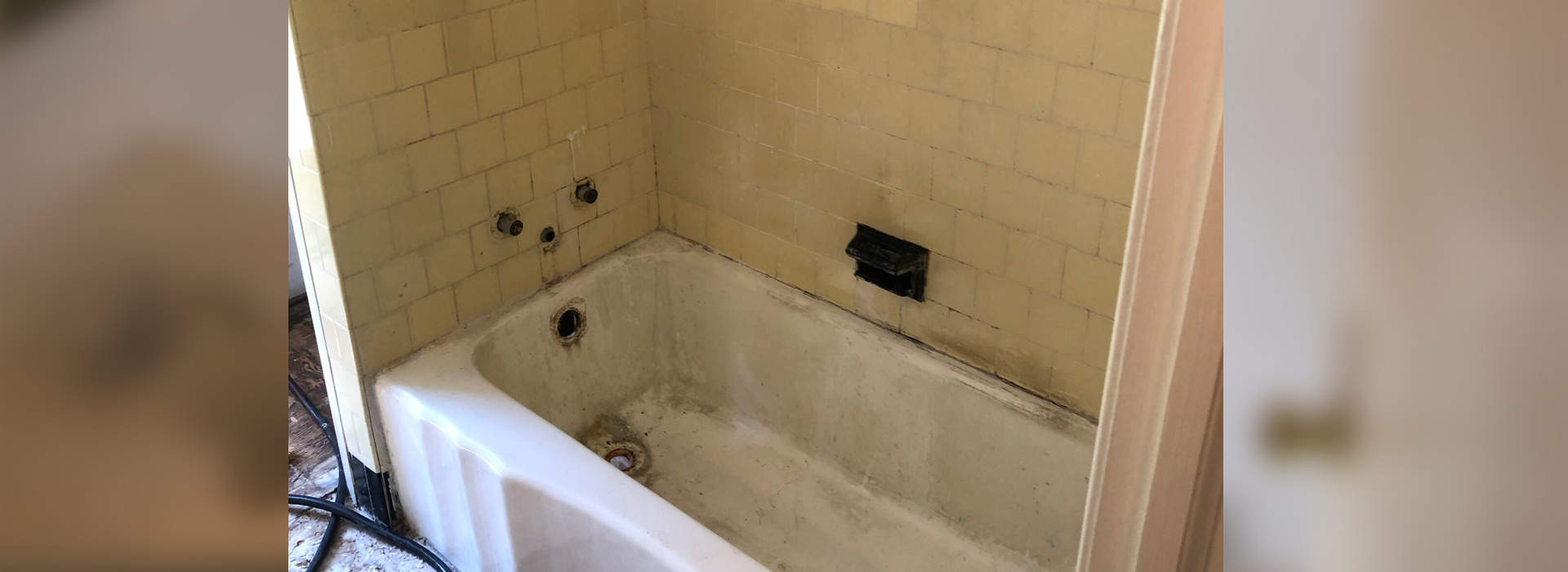 A bathtub in a bathroom with a yellow tiled floor.