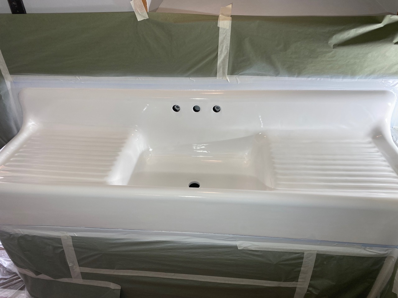 A white sink is being painted in a room.