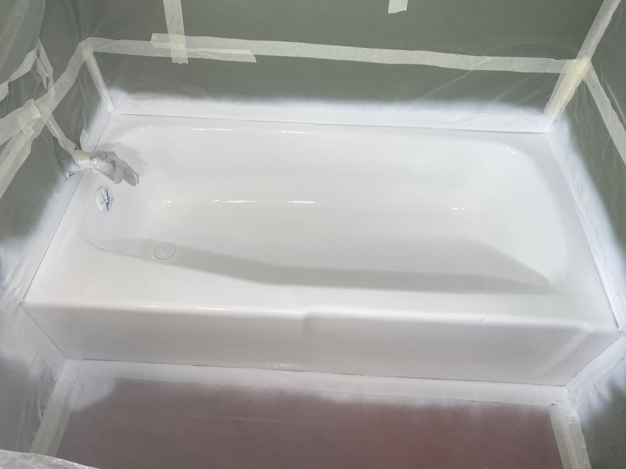 A white bathtub is being painted in a bathroom.