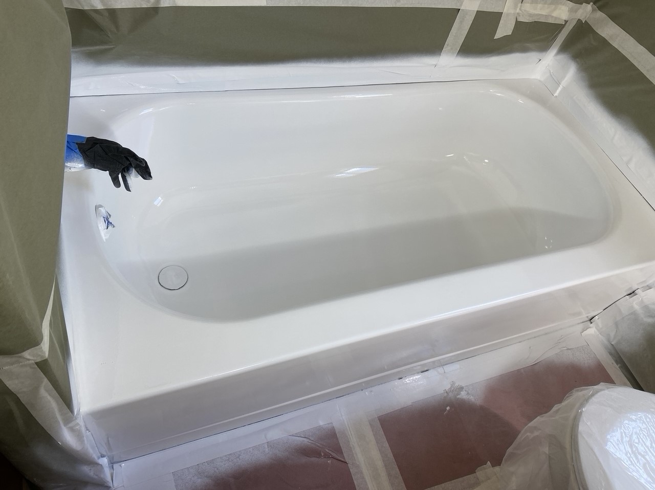 A bathtub being painted in a bathroom.