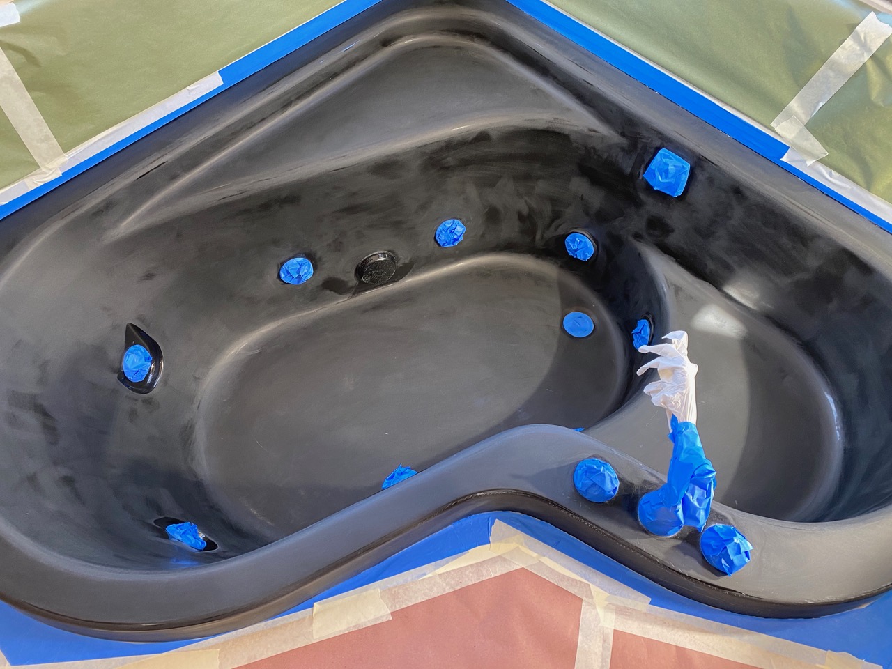 A bathtub is being painted with blue and black paint.