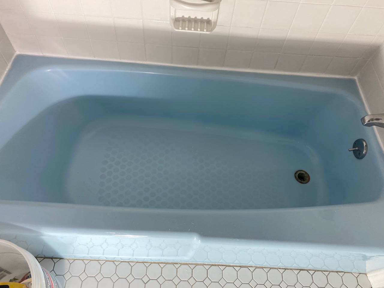 A bathtub that is painted blue and has been cleaned.